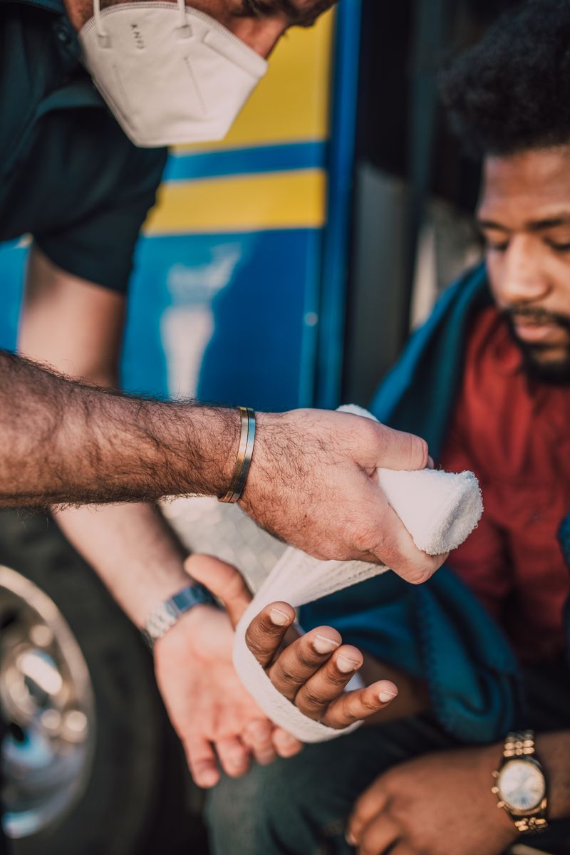 Paramedic wrapping a bandage around a man's arm