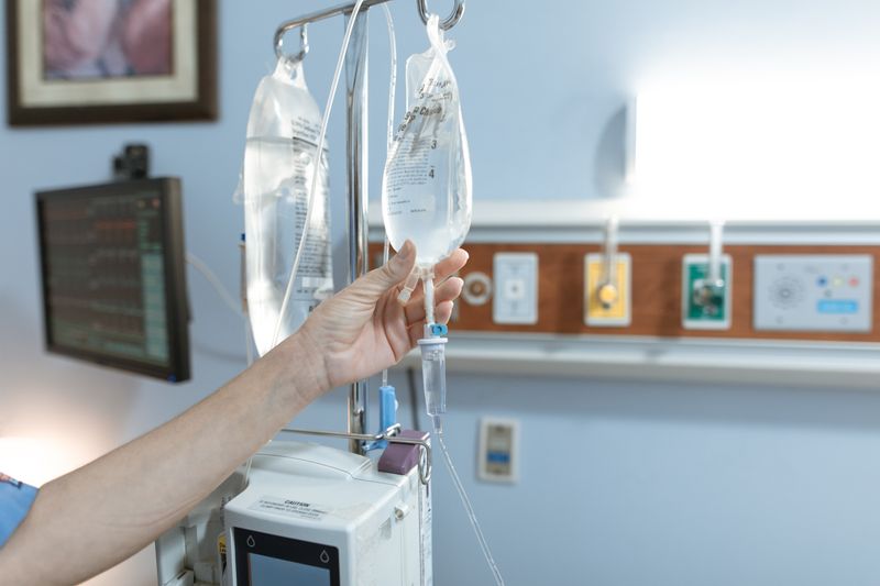 Hand adjusting an IV drip in a clinical setting