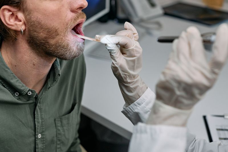 Doctor examining a patient's throat with a tongue depressor