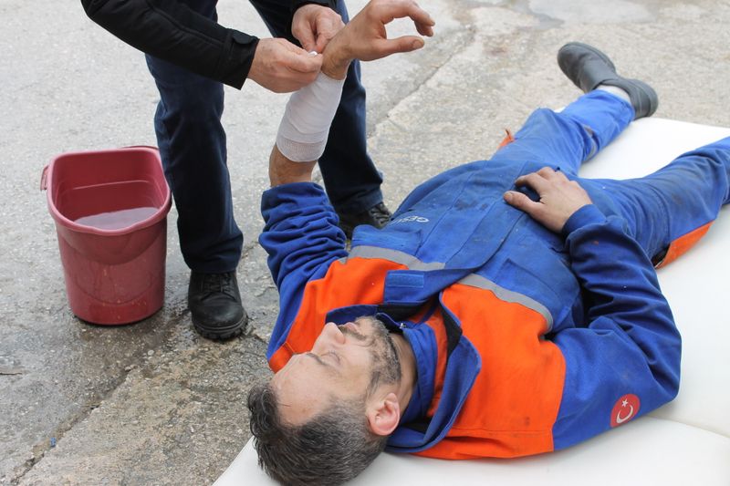 Injured worker in uniform receiving first aid with an arm bandage